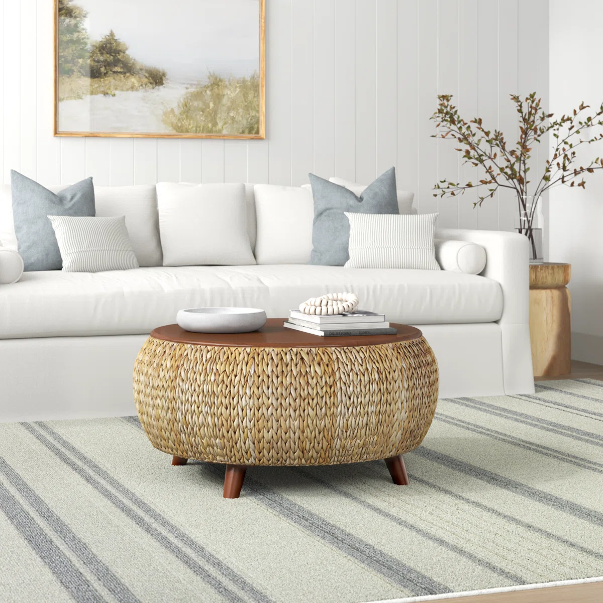 Round lift-top coffee table with solid wood top and woven wicker base, featuring hidden storage and four slanted legs.
