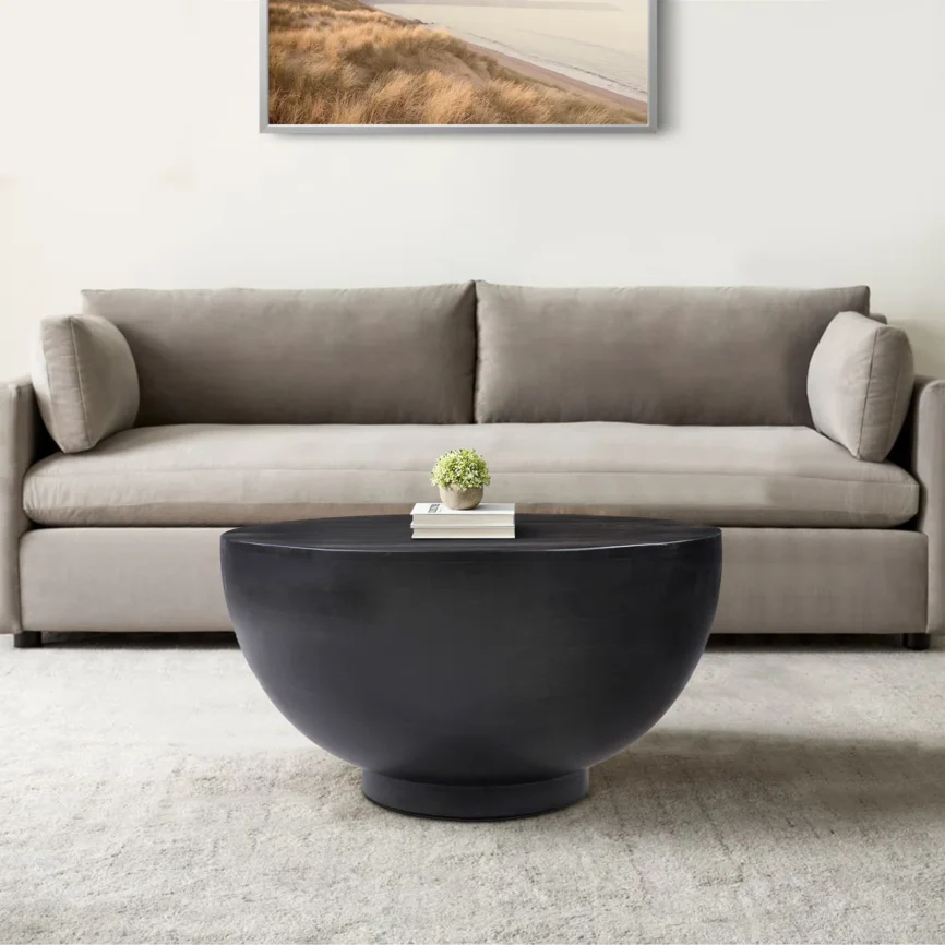 Ebonora round solid wood coffee table with matte black finish, drum silhouette, and tapered base, 76 cm wide.