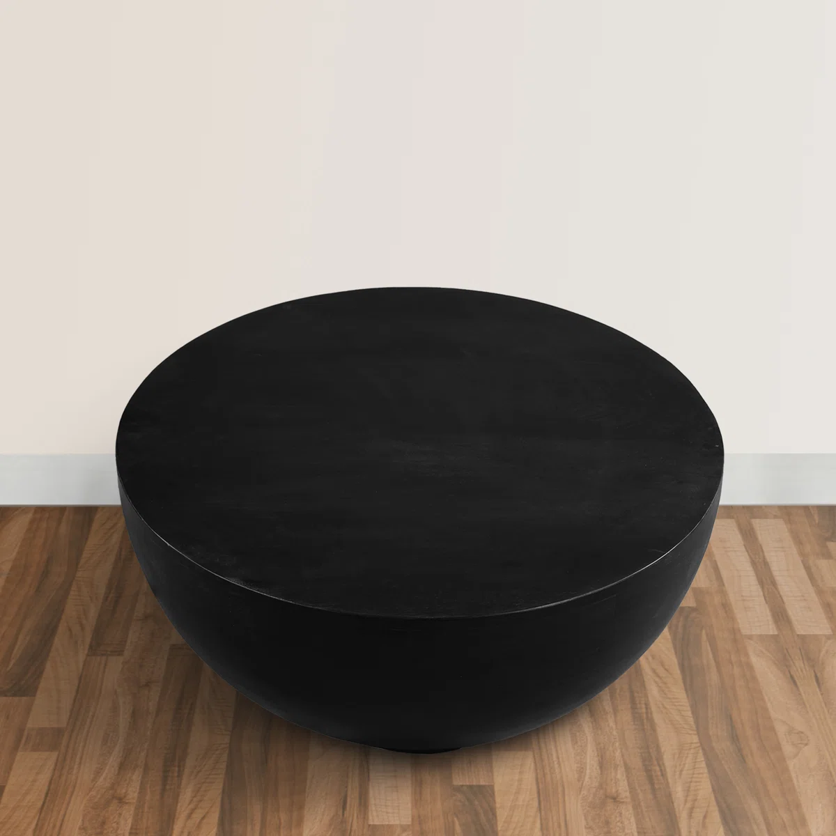 Ebonora round solid wood coffee table with matte black finish, drum silhouette, and tapered base, 76 cm wide.