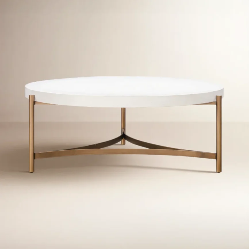 Round white concrete coffee table with brushed bronze stainless steel base, tubular legs, and curved stretchers.