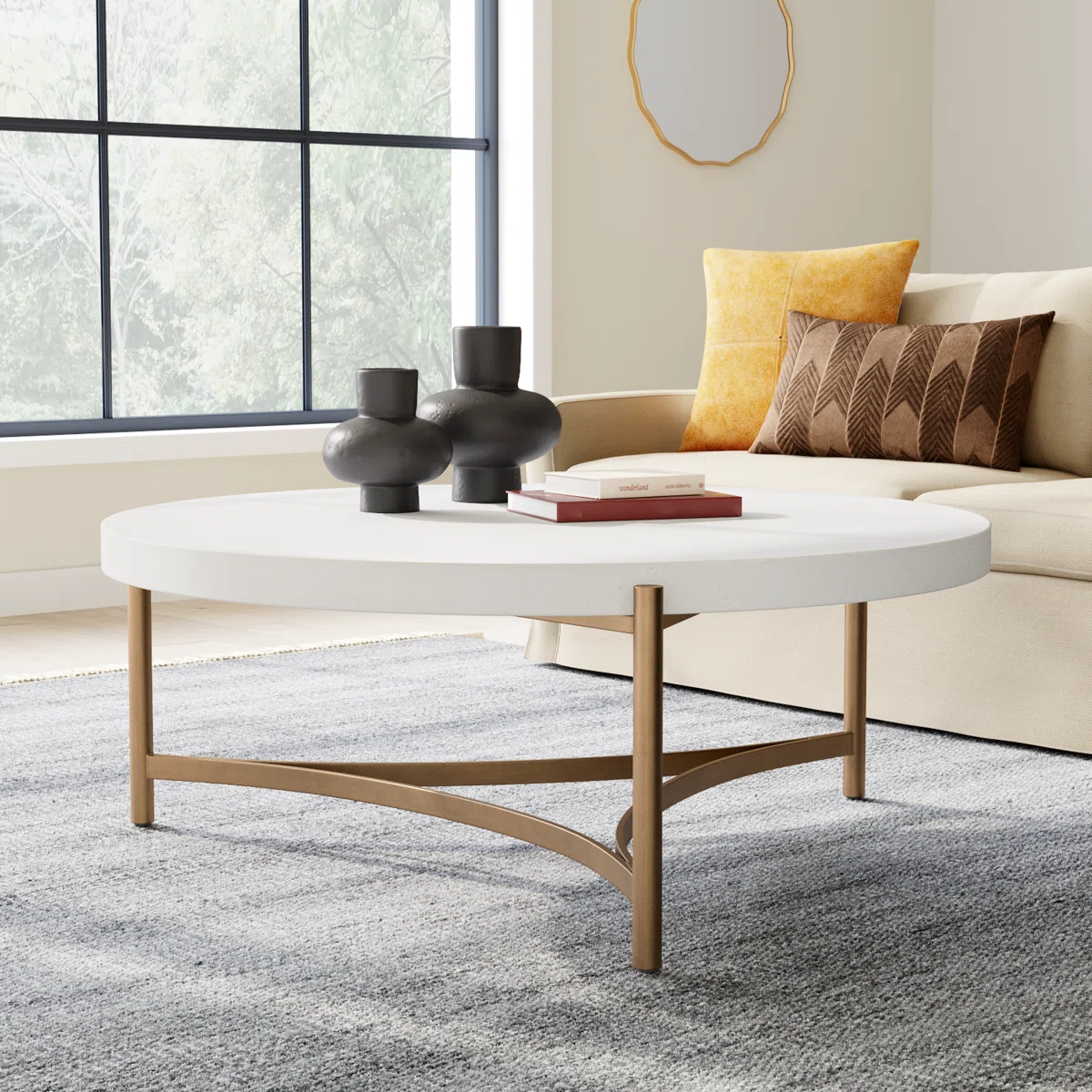 Round white concrete coffee table with brushed bronze stainless steel base, tubular legs, and curved stretchers.