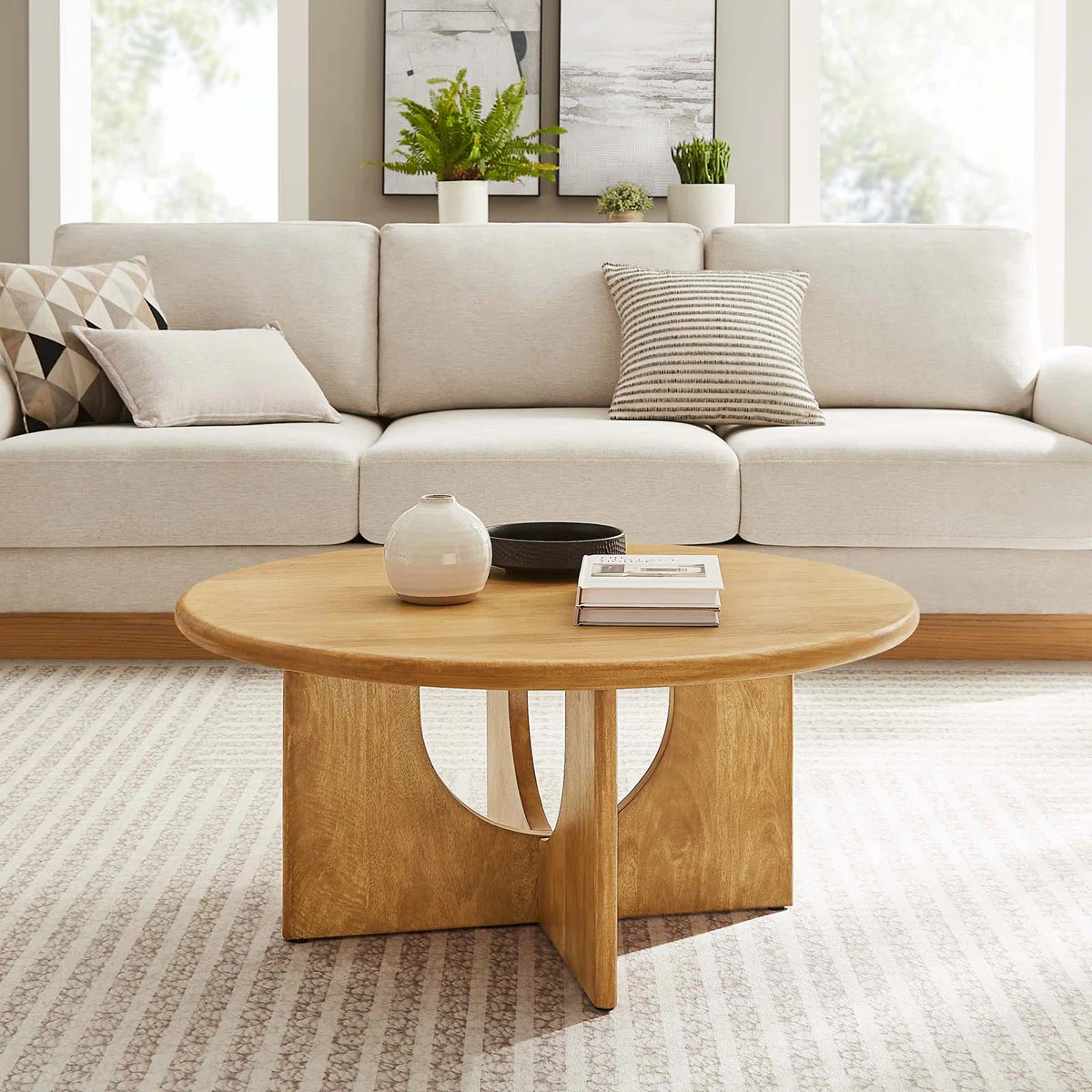 Round solid mango wood coffee table with sculptural pedestal base featuring intersecting arched cutouts